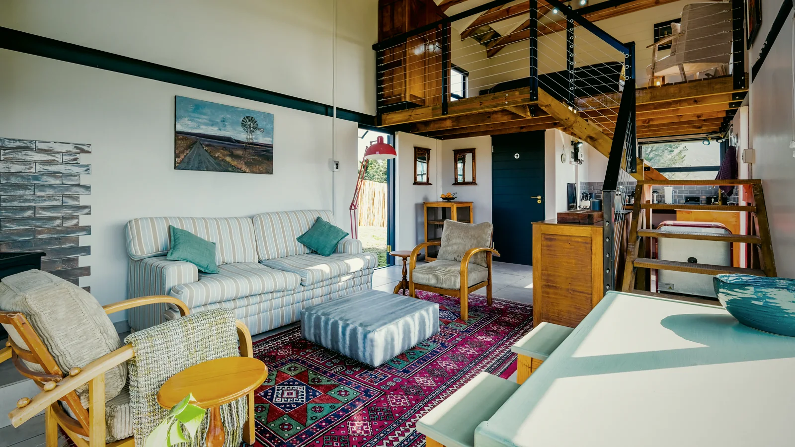 Double-height living room with timber loft, large windows and red floor lamp